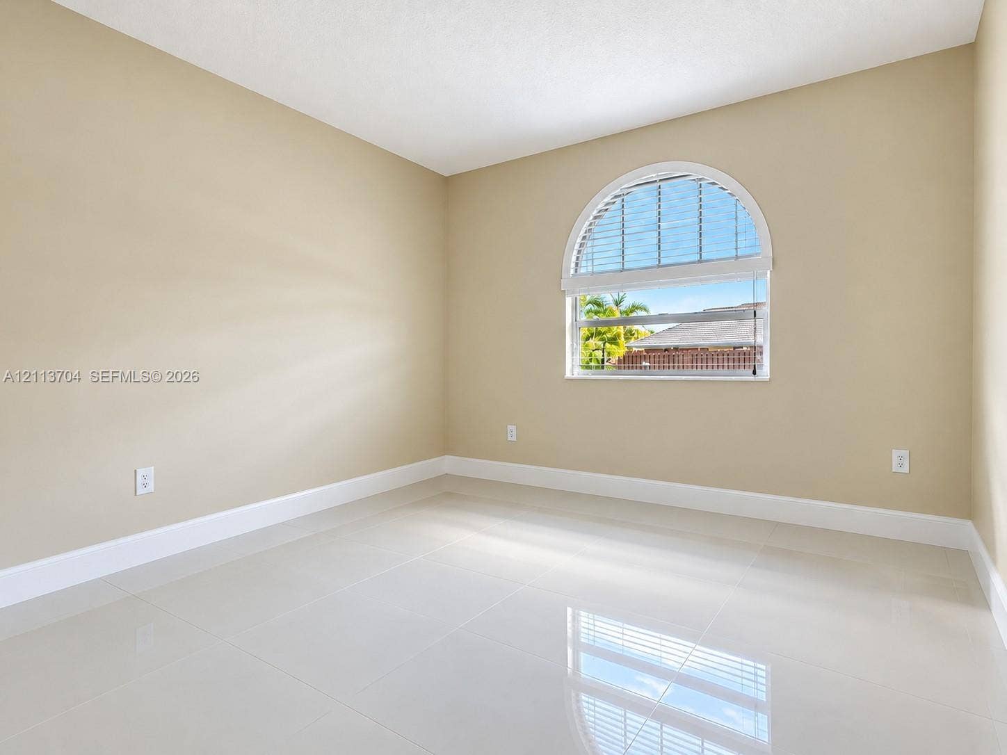 5254 SW 153rd Court, Miami, FL 33185 Neutral-toned interior featuring large-format tile flooring and an arched window with an integrated blind