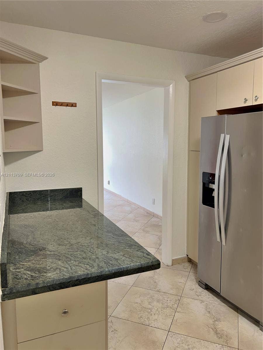 5170 SW 40th Avenue, #1E, Dania, Dania Beach, FL 33314 Kitchen featuring stone countertops, built-in cabinetry, an integrated refrigerator, open shelving, and tile flooring