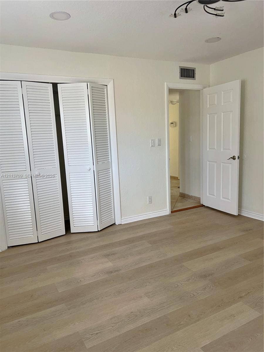 5170 SW 40th Avenue, #1E, Dania, Dania Beach, FL 33314 Wood-finish flooring, white louvered bifold closet doors, recessed ceiling lighting, and a six-panel interior door