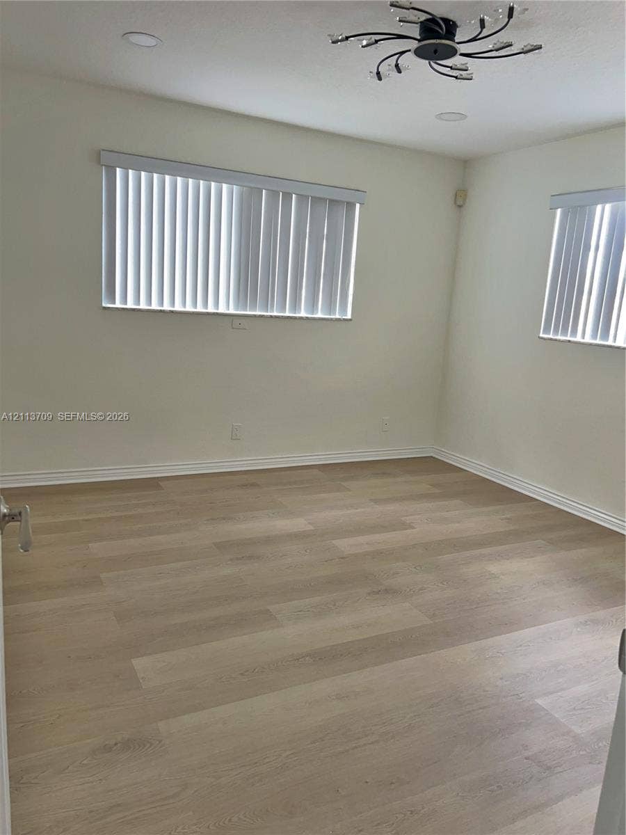 5170 SW 40th Avenue, #1E, Dania, Dania Beach, FL 33314 Light-filled room featuring wood-finish flooring, recessed lighting, a modern multi-arm ceiling fixture, and dual windows with vertical blinds