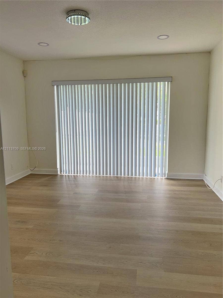 5170 SW 40th Avenue, #1E, Dania, Dania Beach, FL 33314 Neutral-toned room featuring wood-finish flooring, recessed lighting, and vertical window blinds