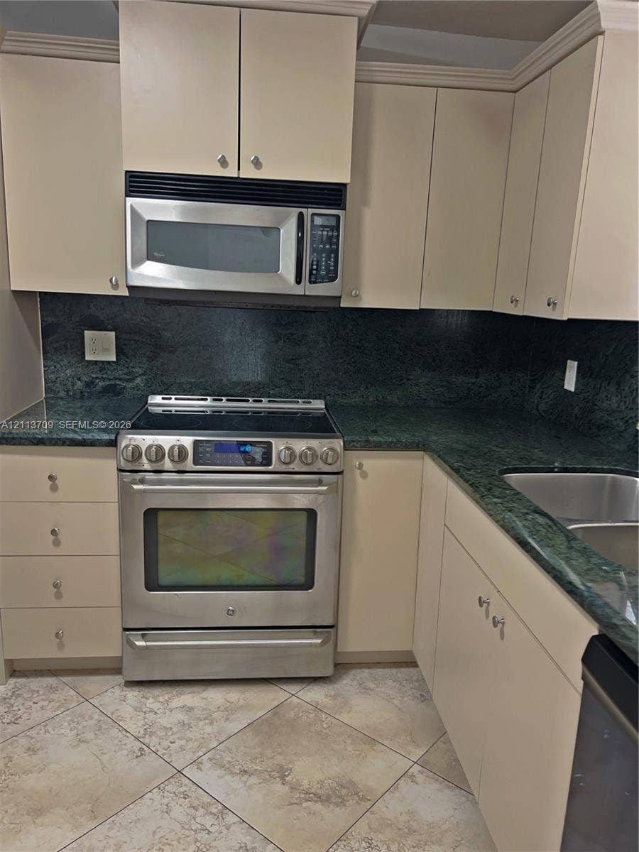 5170 SW 40th Avenue, #1E, Dania, Dania Beach, FL 33314 Kitchen featuring stone countertops, stainless steel appliances, upper and lower cabinetry, a dual-basin undermount sink, and tile flooring