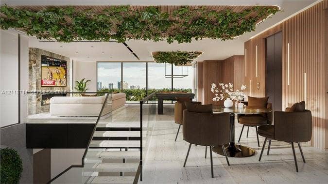 3322 NE 16th Court, Fort Lauderdale, FL 33305 Open-concept interior featuring light-toned stone flooring, floor-to-ceiling windows, slatted wood-finish wall paneling, a stone-surround fireplace, and a glass-paneled staircase