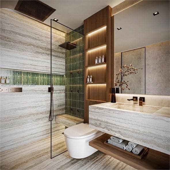 3322 NE 16th Court, Fort Lauderdale, FL 33305 Stone-tiled bathroom featuring a glass-enclosed walk-in shower with integrated wall-mounted shower heads, vertical green tile accents, wood-finish built-in shelving with recessed lighting, and a wall-mounted floating vanity