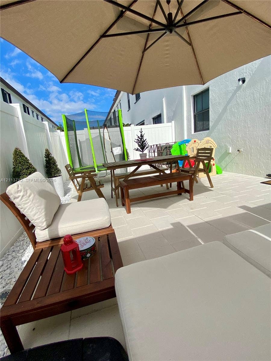 10906 W 33rd Court, Hialeah, FL 33018 Private courtyard featuring light-toned paver flooring and white vinyl privacy fencing
