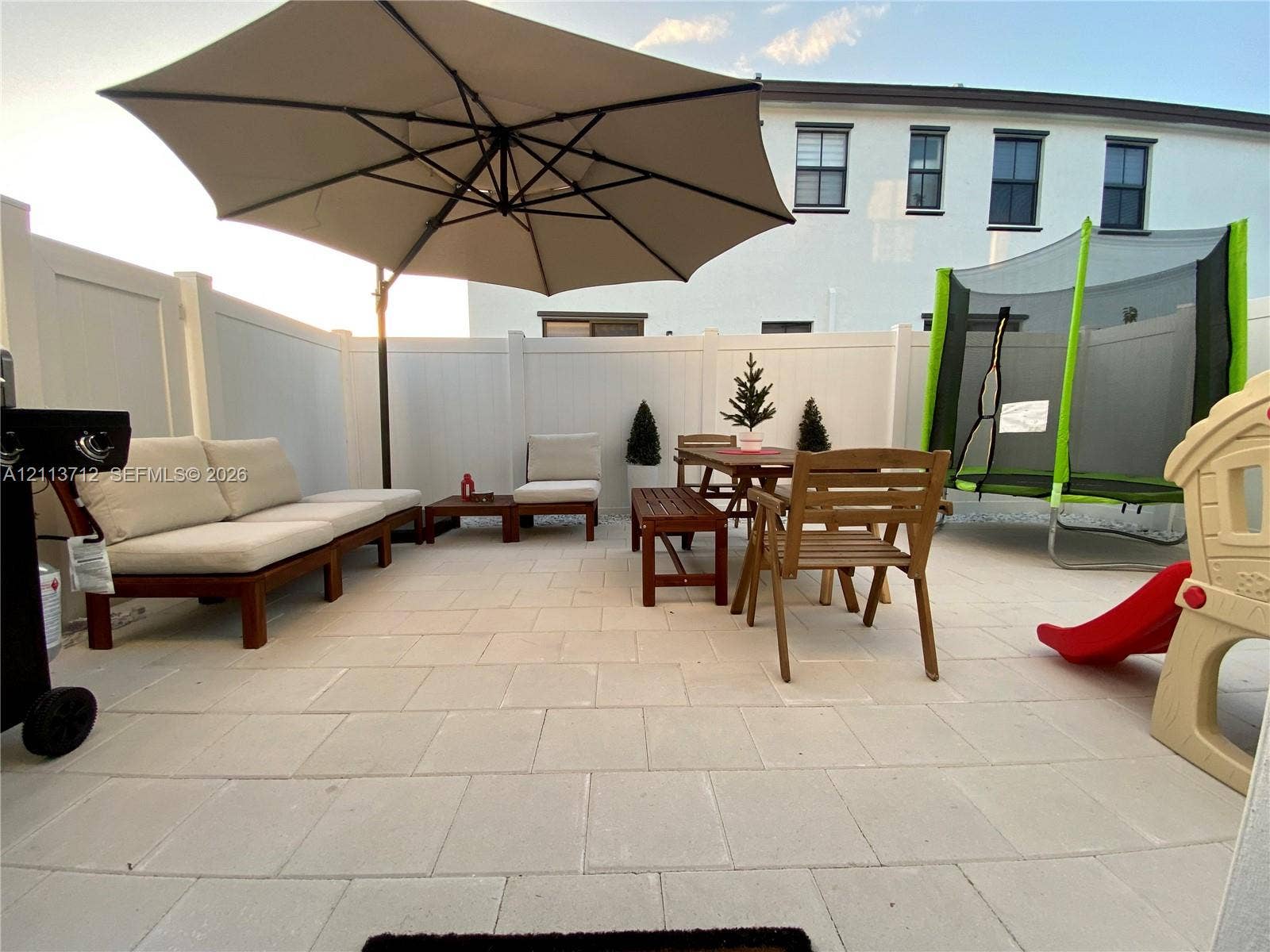 10906 W 33rd Court, Hialeah, FL 33018 Private patio featuring light-toned concrete pavers enclosed by a white vinyl privacy fence