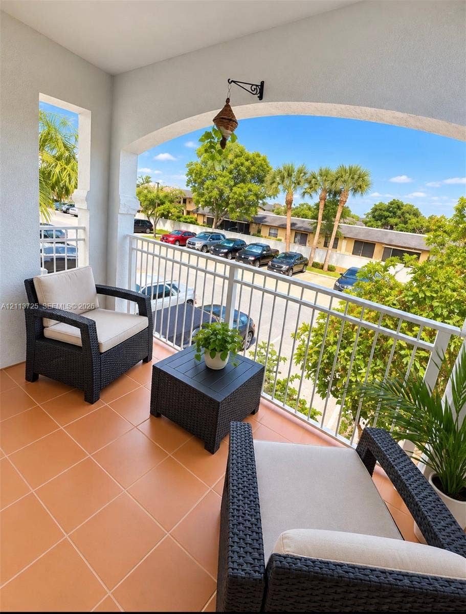 Covered balcony featuring a white metal railing, arched ceiling detail, and ceramic tile flooring