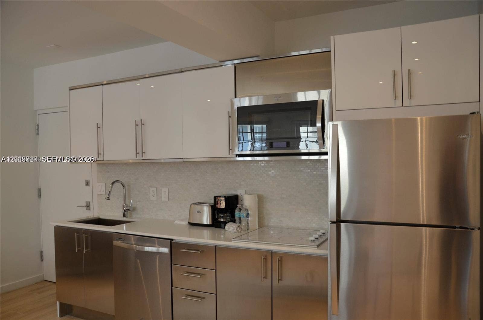 700 SE 16th Street, #201, Miami Beach, Miami Beach, FL 33139 Kitchen featuring high-gloss white upper cabinetry, stainless steel lower cabinetry, solid-surface countertops, mosaic tile backsplash, and stainless steel appliances