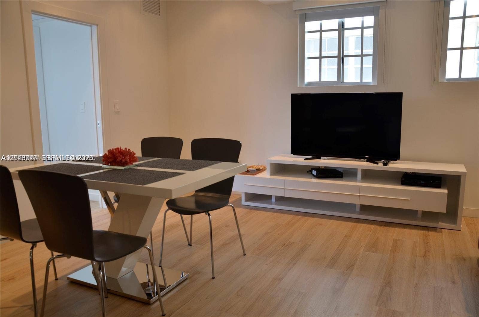 700 SE 16th Street, #201, Miami Beach, Miami Beach, FL 33139 Neutral interior featuring light-tone wood-finish flooring, white built-in media cabinetry, and double-hung windows with mullions