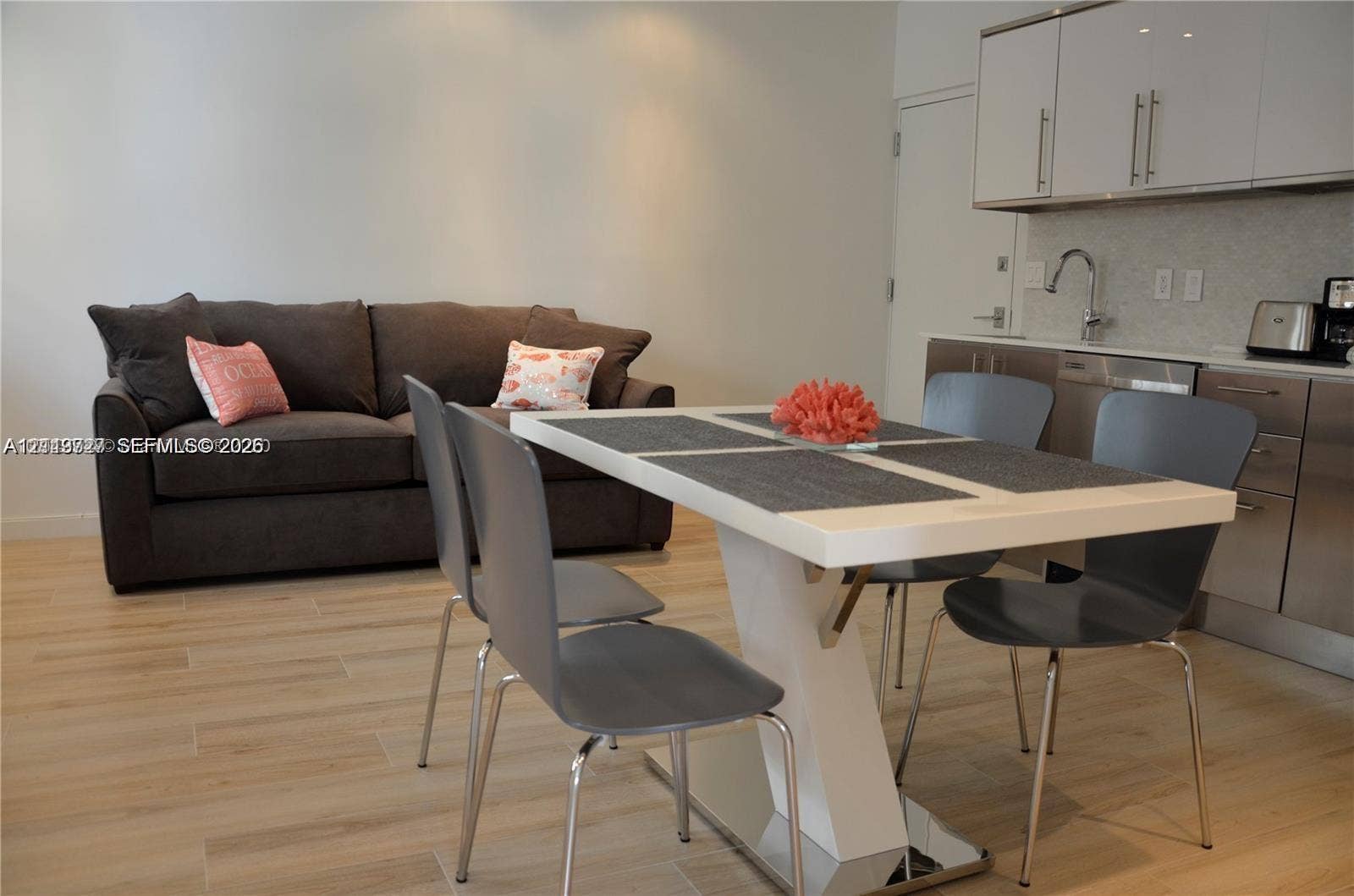 700 SE 16th Street, #201, Miami Beach, Miami Beach, FL 33139 Kitchen featuring high-gloss upper cabinetry, stainless steel lower cabinets, stone-finish backsplash, wood-finish flooring, and a gooseneck faucet