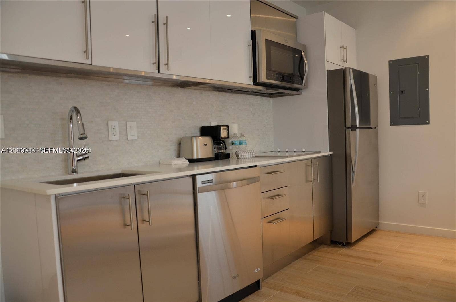 700 SE 16th Street, #201, Miami Beach, Miami Beach, FL 33139 Kitchen featuring flat-panel white cabinetry, stainless steel appliances, stone-finish countertops, high-arc faucet, and wood-finish flooring
