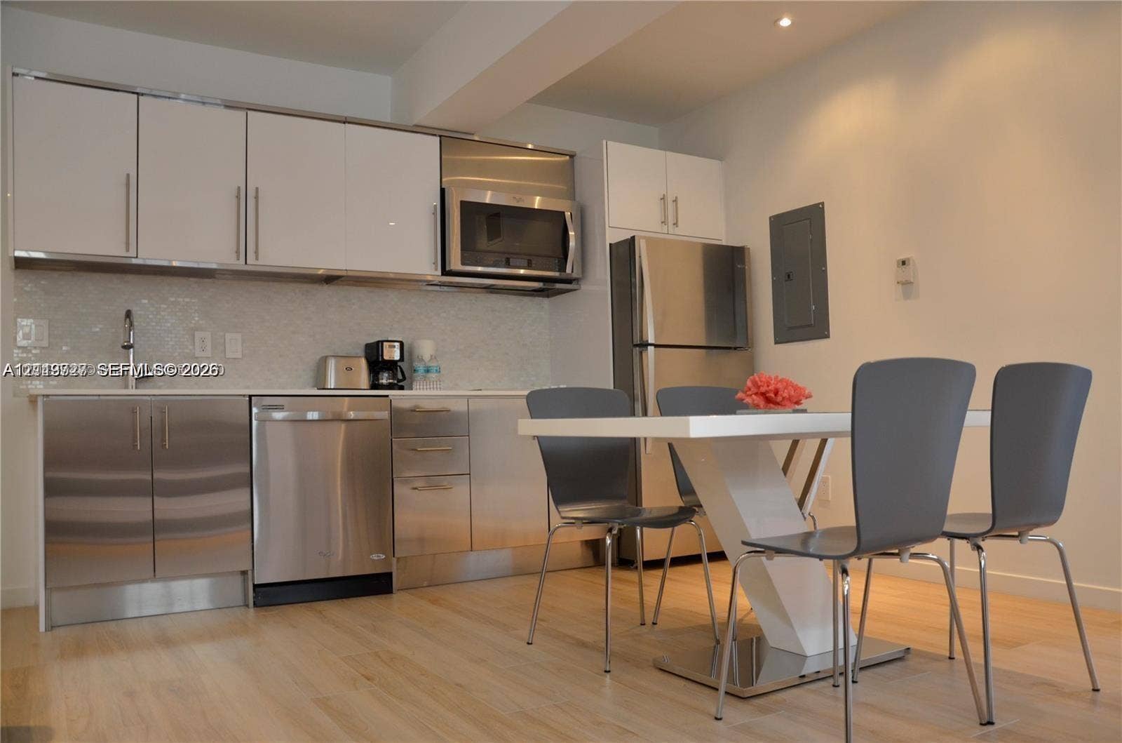 700 SE 16th Street, #201, Miami Beach, Miami Beach, FL 33139 Kitchen featuring high-gloss white upper cabinetry, stainless steel lower cabinetry, built-in stainless steel microwave, integrated dishwasher, and light-toned wood-finish flooring