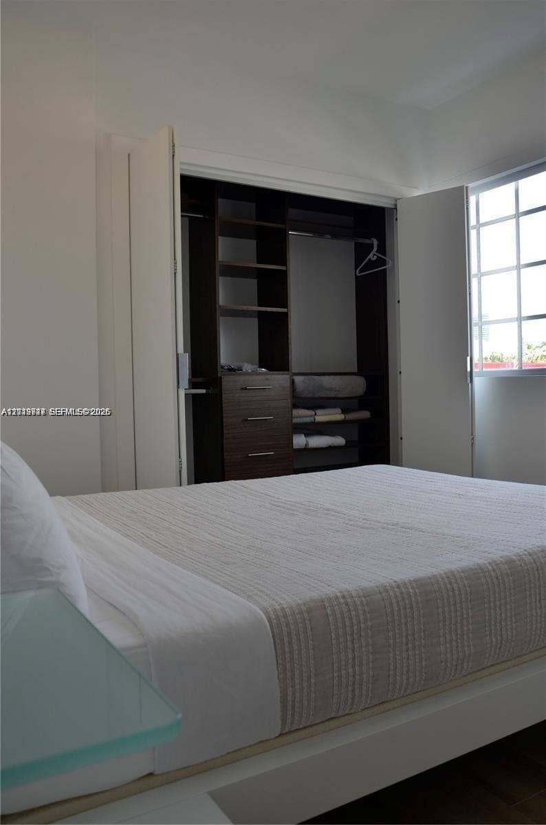 700 SE 16th Street, #201, Miami Beach, Miami Beach, FL 33139 Closet featuring custom dark wood-finish shelving, built-in drawer storage, and double-fold doors, complemented by a grid-pane window