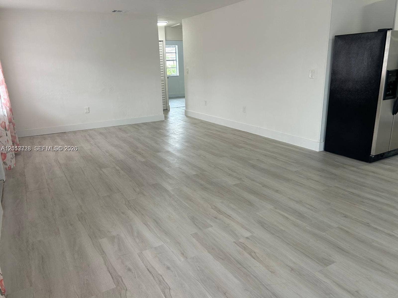 9200 SW 37th Street, Miami, FL 33165 Open-concept interior featuring light-toned wood-finish flooring, neutral walls, and a stainless steel refrigerator