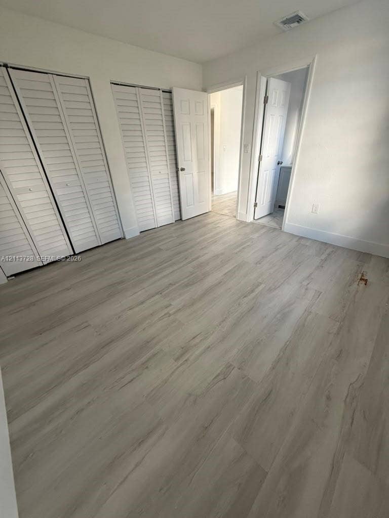 9200 SW 37th Street, Miami, FL 33165 Interior space featuring wood-finish flooring, two sets of white louvered-style closet doors, and multi-panel interior doors