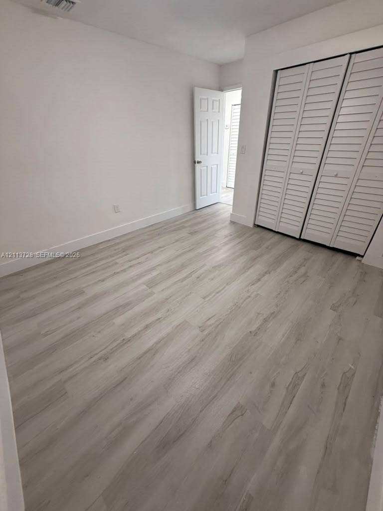 9200 SW 37th Street, Miami, FL 33165 Interior room featuring wood-finish flooring, white walls, and a closet with white louvered bi-fold doors