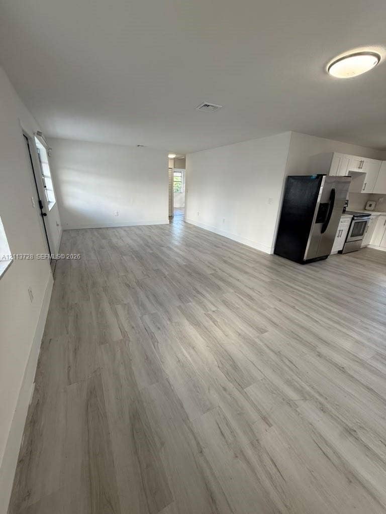 9200 SW 37th Street, Miami, FL 33165 Open-concept interior featuring light wood-finish flooring, white cabinetry, stainless steel appliances, and flush-mount ceiling lighting