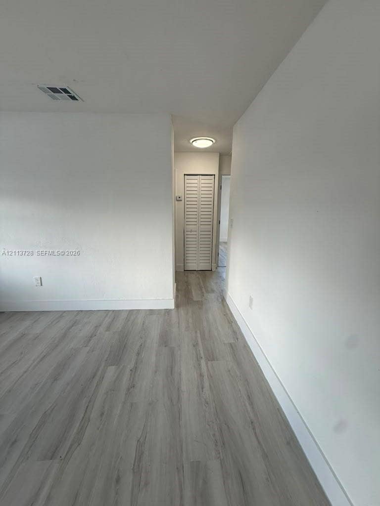 9200 SW 37th Street, Miami, FL 33165 Wood-finish flooring, neutral walls, and a closet with white louvered doors