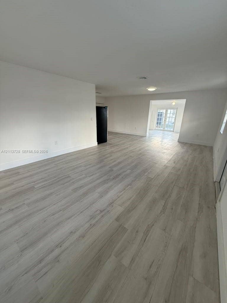 9200 SW 37th Street, Miami, FL 33165 Open-concept interior featuring wood-finish flooring, recessed lighting, and white walls, complete with a glass-paned double door entrance