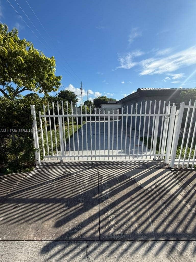 9200 SW 37th Street, Miami, FL 33165 White metal picket gate with vertical bars and concrete driveway