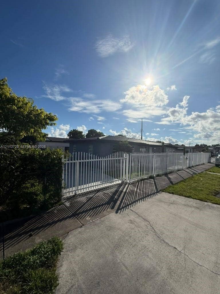 9200 SW 37th Street, Miami, FL 33165 Exterior of a single-story residence featuring a perimeter metal privacy fence and gated driveway access