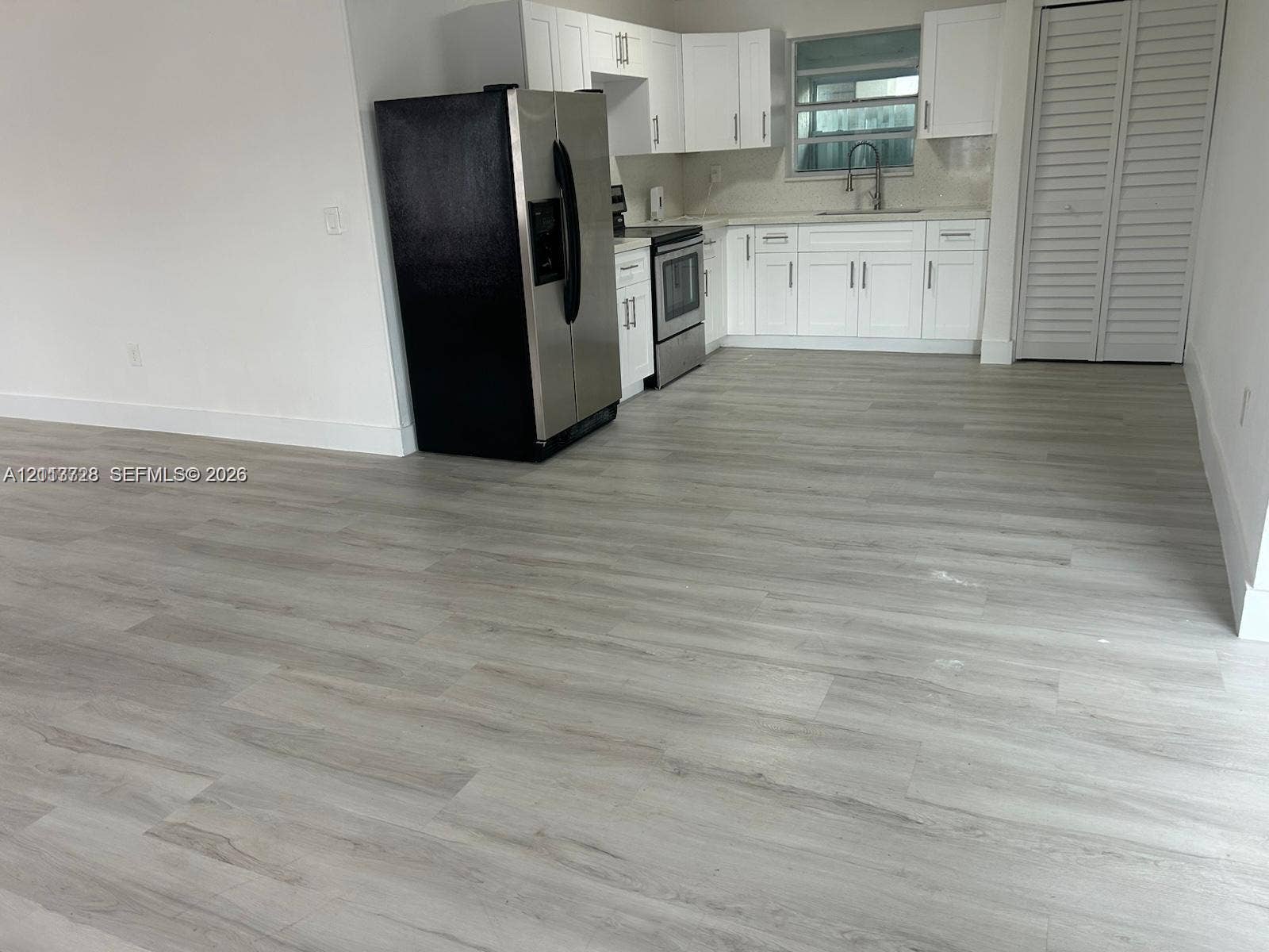 9200 SW 37th Street, Miami, FL 33165 Kitchen featuring white shaker-style cabinetry, wood-finish flooring, stainless steel appliances, and a recessed faucet