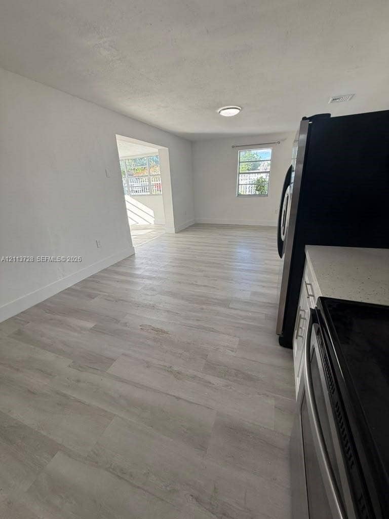 9200 SW 37th Street, Miami, FL 33165 Light-toned wood-finish flooring, white cabinetry, light-colored countertops, and stainless steel appliances