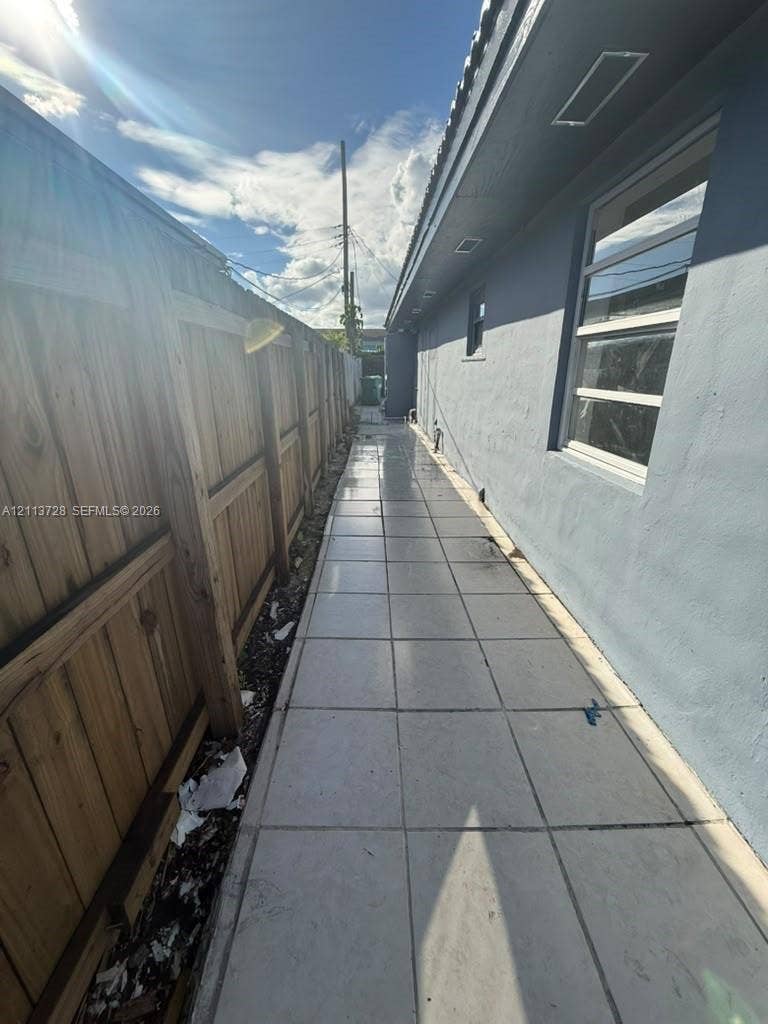 9200 SW 37th Street, Miami, FL 33165 Exterior side yard featuring large-format tile paving and a wood-slat privacy fence