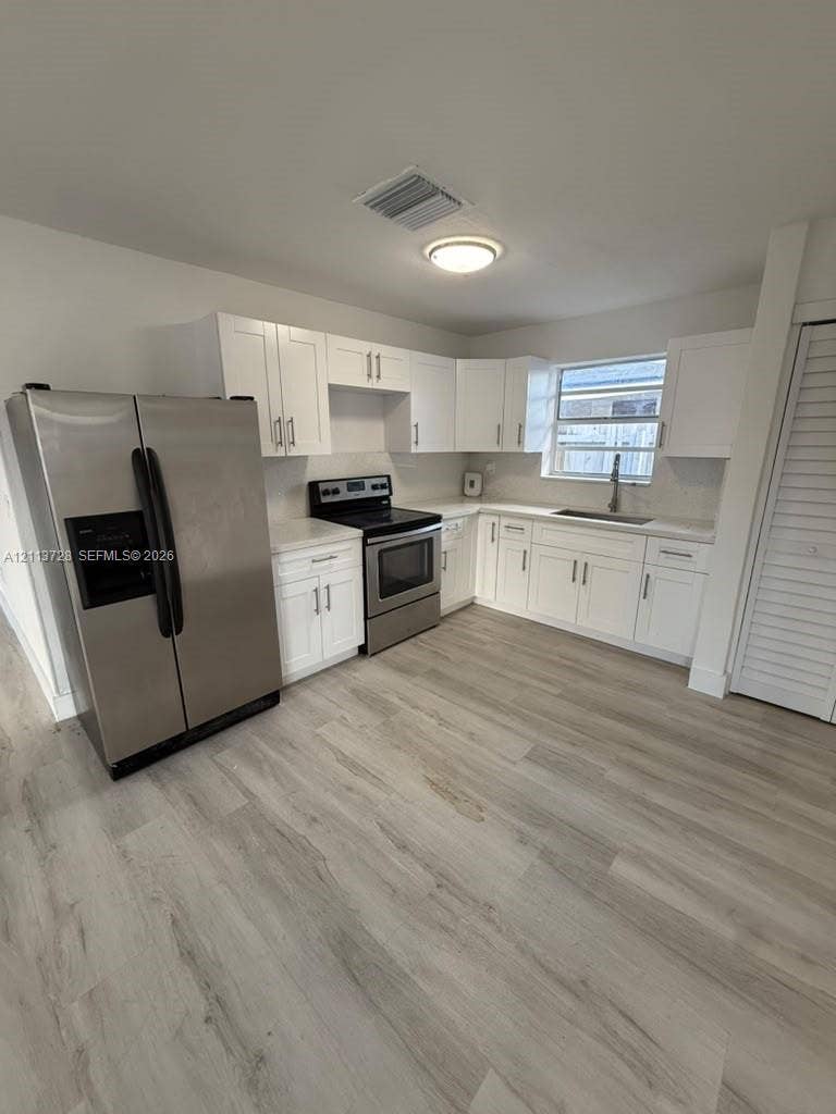 9200 SW 37th Street, Miami, FL 33165 Kitchen featuring white shaker-style cabinetry, stainless steel appliances, light-toned stone countertops, and wood-finish flooring