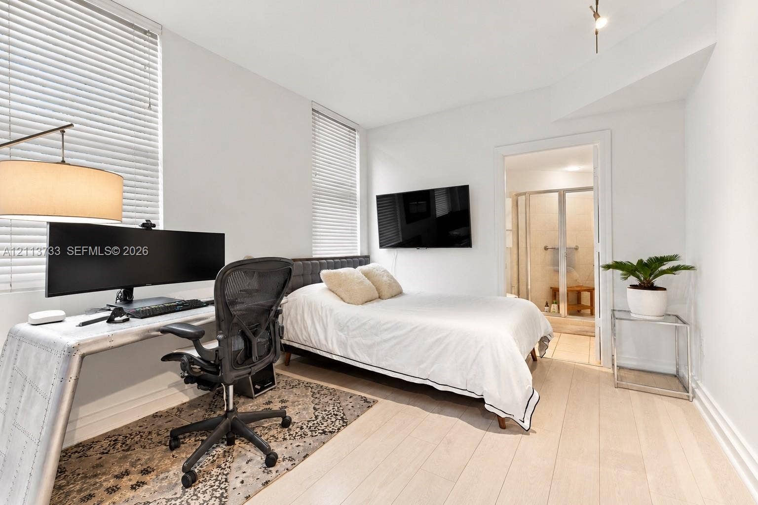 9751 E Bay Harbor Drive, #6A, Bay Harbor Islands, FL 33154 Light-filled room featuring wood-finish flooring, tall windows with horizontal blinds, and a neutral color palette