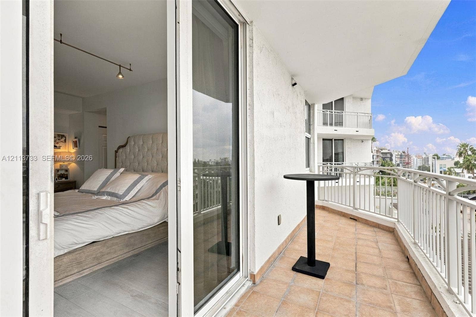 9751 E Bay Harbor Drive, #6A, Bay Harbor Islands, FL 33154 Private balcony featuring tile flooring and white metal railing, accessed through sliding glass doors