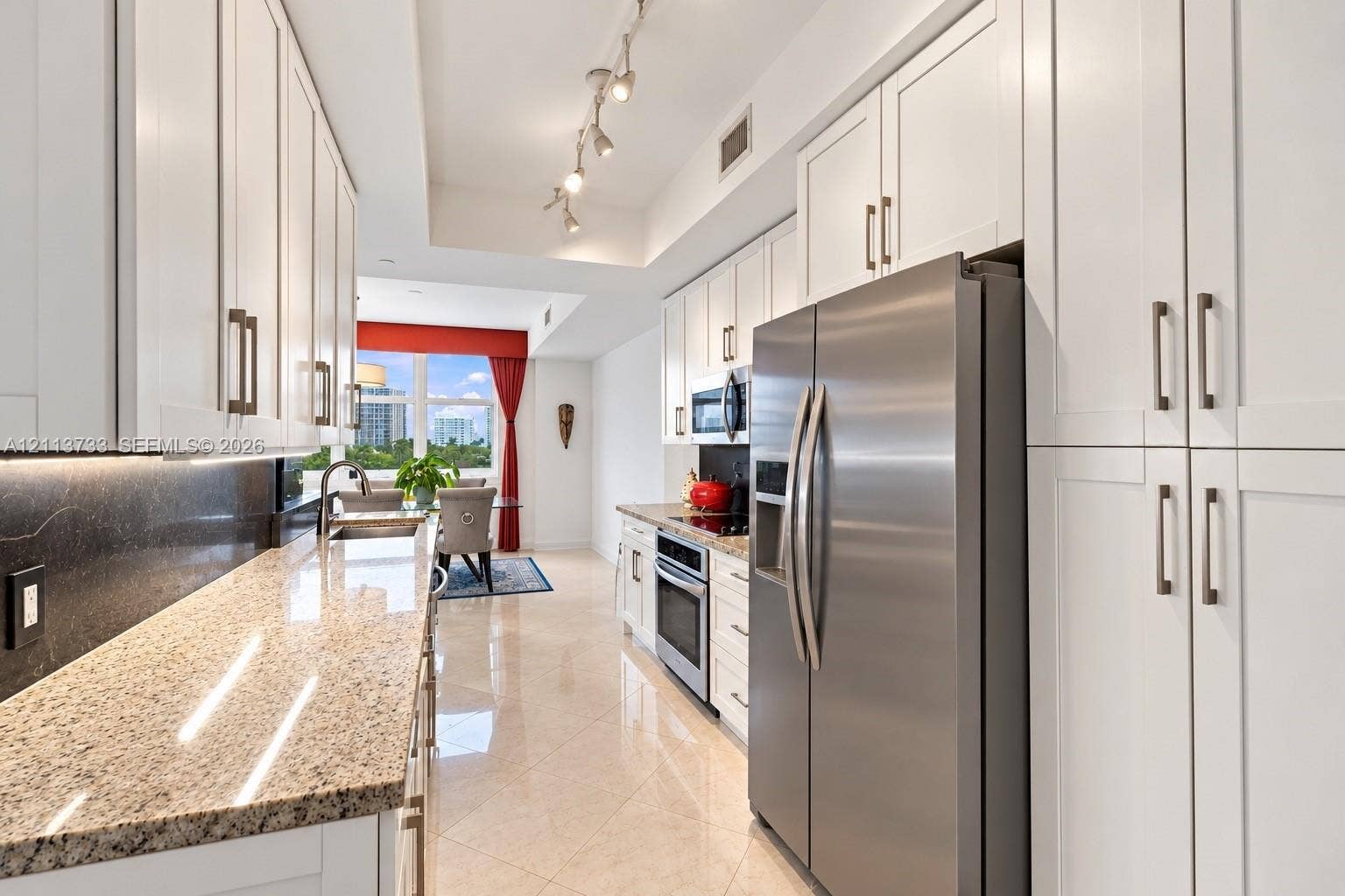 9751 E Bay Harbor Drive, #6A, Bay Harbor Islands, FL 33154 Kitchen featuring white shaker-style cabinetry, stone countertops, stainless steel appliances, track lighting, and tile flooring