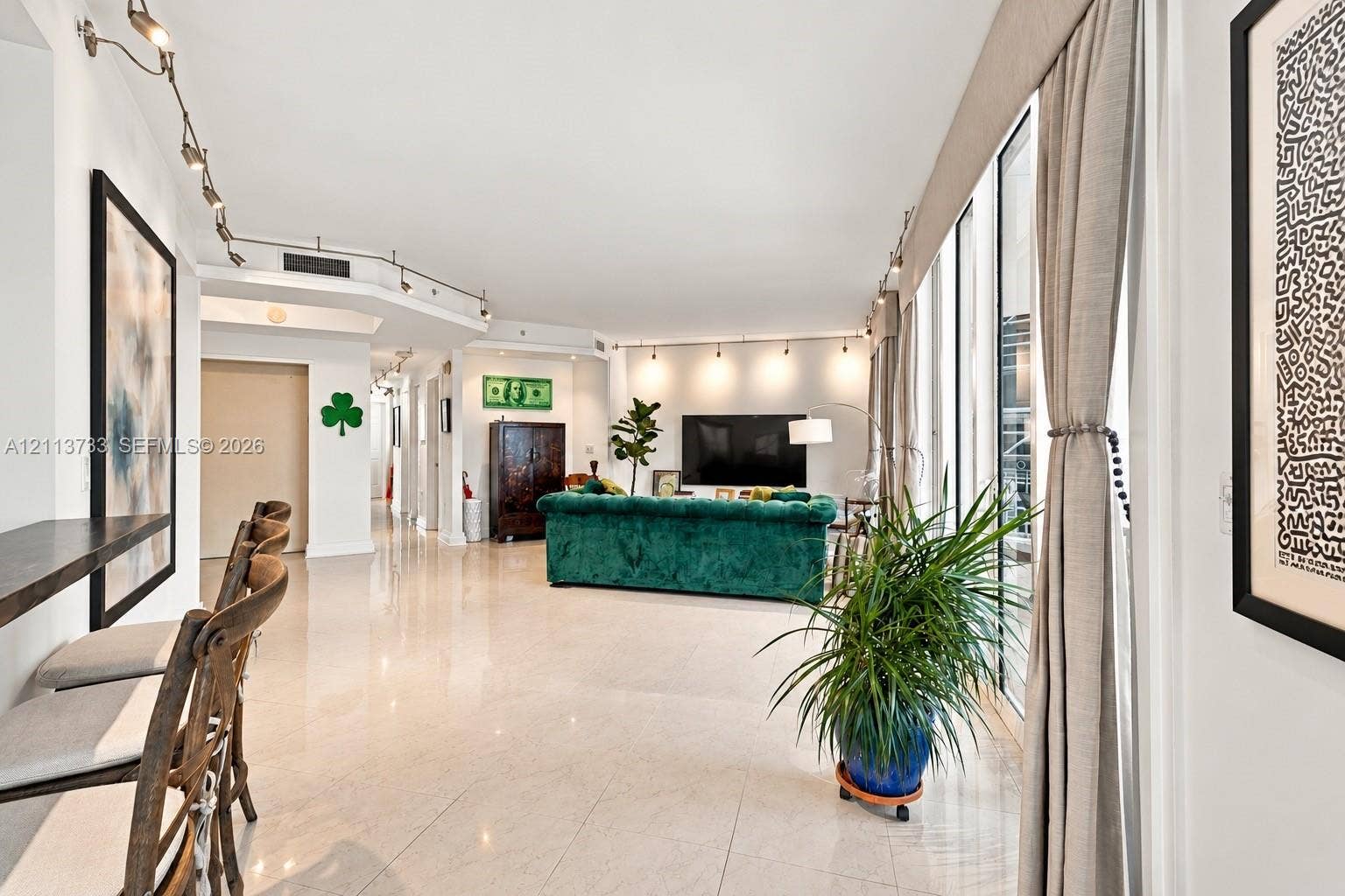 9751 E Bay Harbor Drive, #6A, Bay Harbor Islands, FL 33154 Polished stone flooring, floor-to-ceiling windows, built-in track lighting, and a breakfast bar