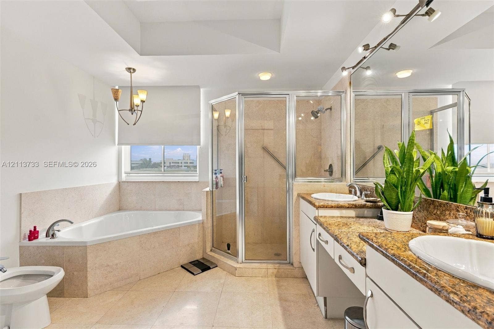 9751 E Bay Harbor Drive, #6A, Bay Harbor Islands, FL 33154 Bathroom featuring a corner soaking tub with stone surround, a glass-enclosed shower, dual-sink vanity with stone countertop, and recessed ceiling lighting