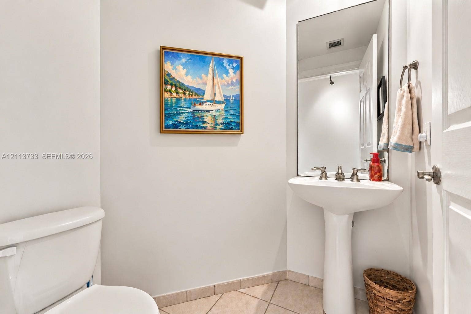 9751 E Bay Harbor Drive, #6A, Bay Harbor Islands, FL 33154 Powder Room: White pedestal sink with a metallic three-handle faucet, large wall-mounted mirror, and neutral-tone tile flooring