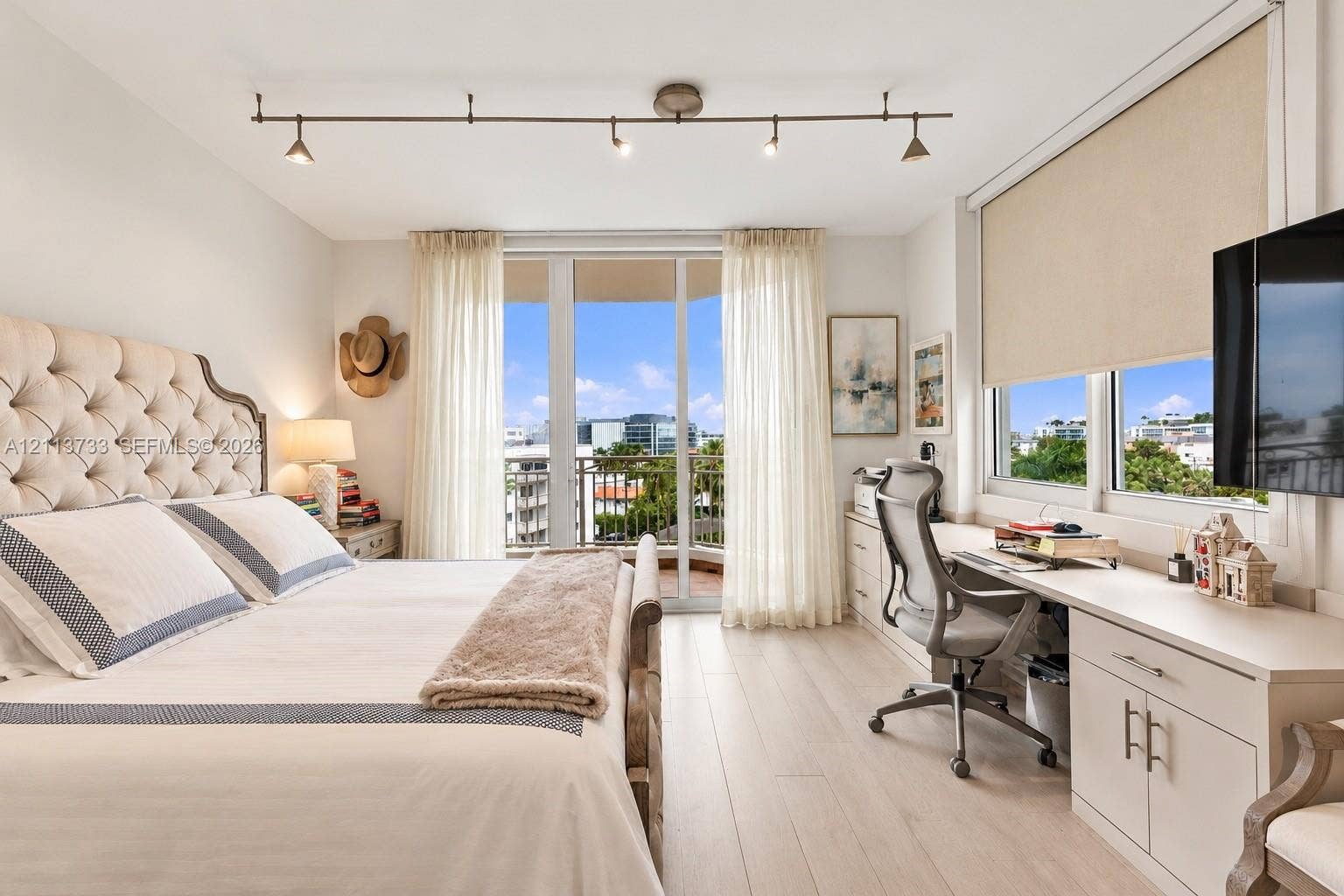 9751 E Bay Harbor Drive, #6A, Bay Harbor Islands, FL 33154 Wood-finish flooring, built-in cabinetry with desktop, floor-to-ceiling glass door opening to a balcony, and adjustable track lighting