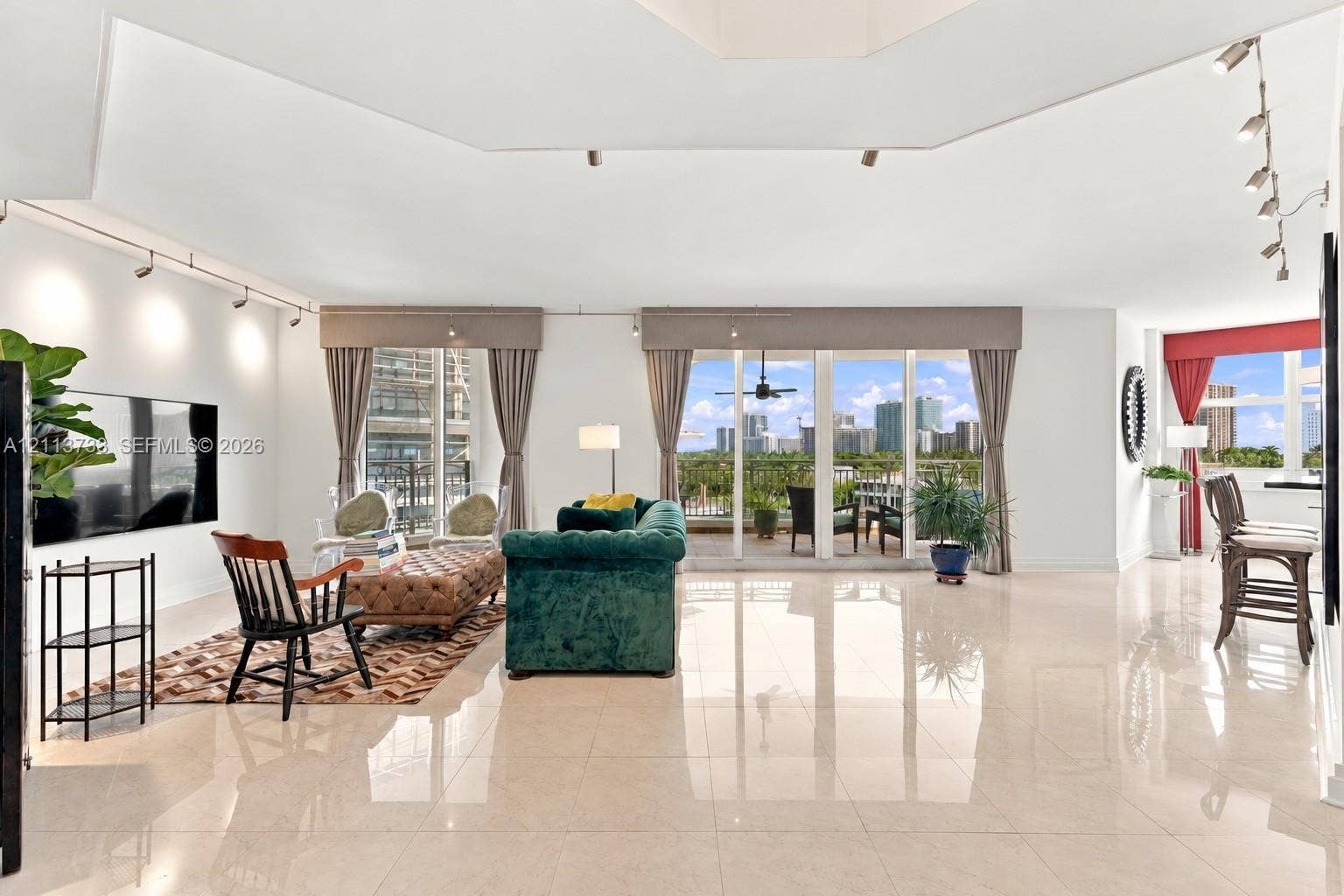 9751 E Bay Harbor Drive, #6A, Bay Harbor Islands, FL 33154 Spacious interior featuring high-gloss tile flooring, vaulted ceilings, adjustable track lighting, and multiple floor-to-ceiling glass panel doors providing access to a balcony