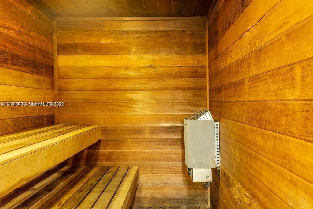 2030 S Ocean Drive, #1719, Hallandale Beach, FL 33009 Sauna room featuring wood-paneled walls, multi-level slatted wood benches, and a wall-mounted electric heater