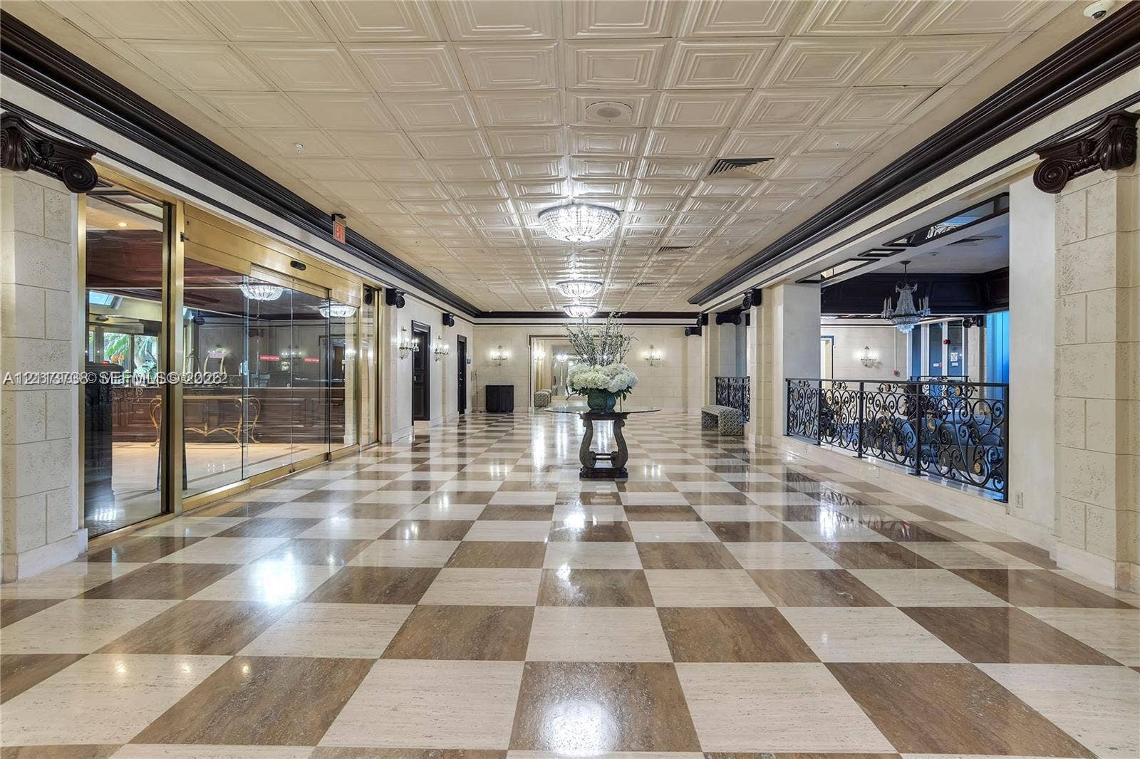 2030 S Ocean Drive, #1719, Hallandale Beach, FL 33009 Grand lobby featuring a coffered ceiling, checkered marble flooring, decorative crown molding, ornamental column capitals, and ornate wrought-iron railings