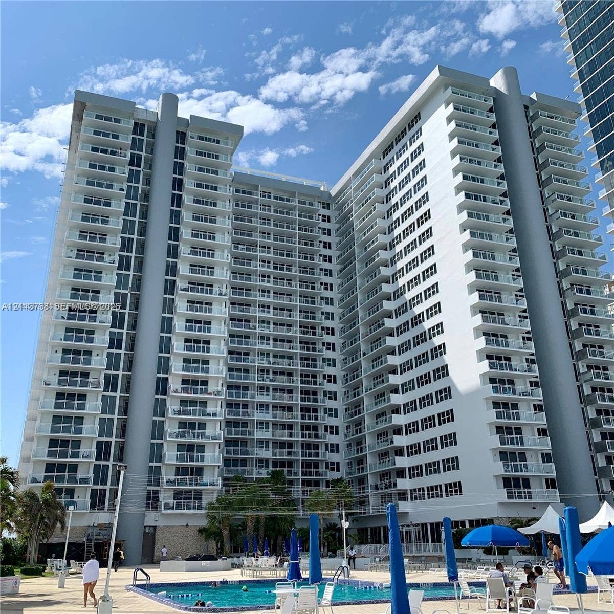 2030 S Ocean Drive, #1719, Hallandale Beach, FL 33009 High-rise residential exterior featuring expansive private balconies, floor-to-ceiling glass windows, a swimming pool, and stone facade accents