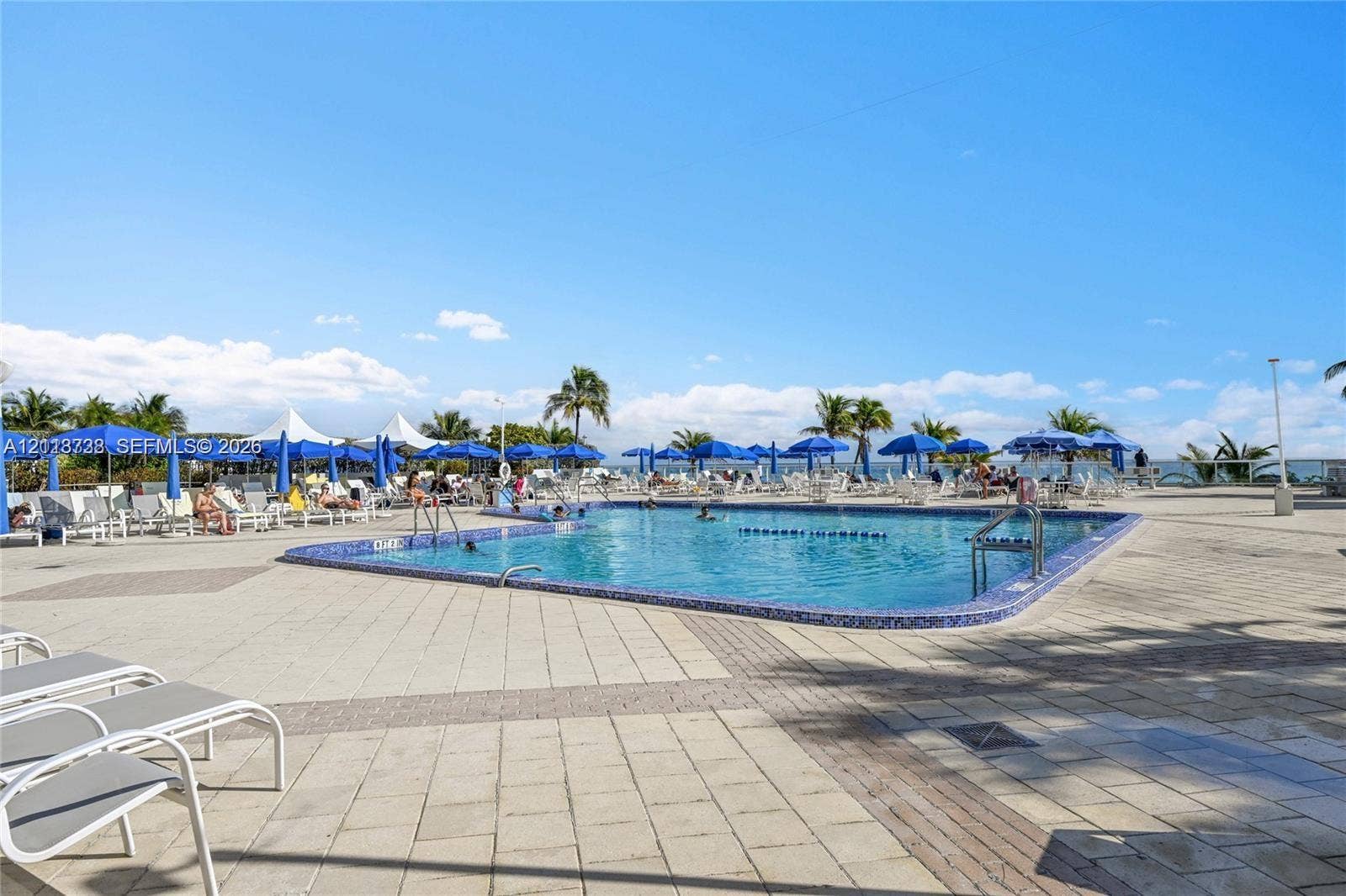 2030 S Ocean Drive, #1719, Hallandale Beach, FL 33009 In-ground swimming pool featuring a mosaic-tile perimeter, metal entry handrails, and a surrounding paved terrace