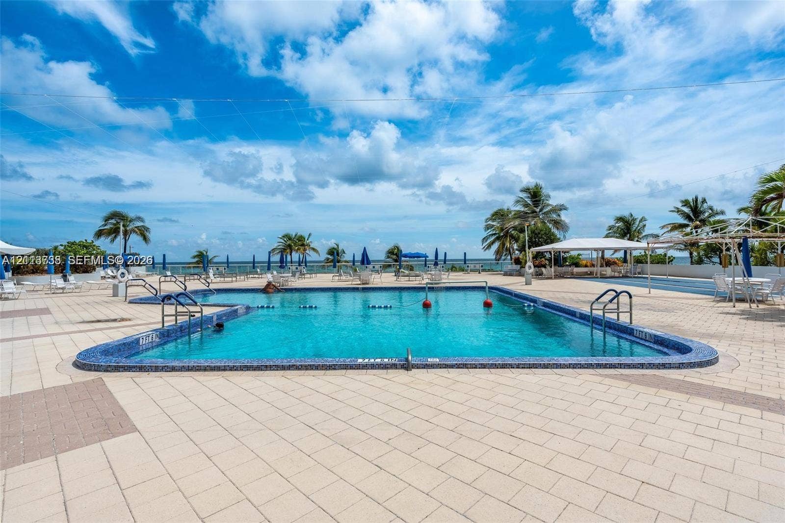 2030 S Ocean Drive, #1719, Hallandale Beach, FL 33009 In-ground swimming pool featuring a tiled waterline, metal entry rails, and expansive paved pool deck