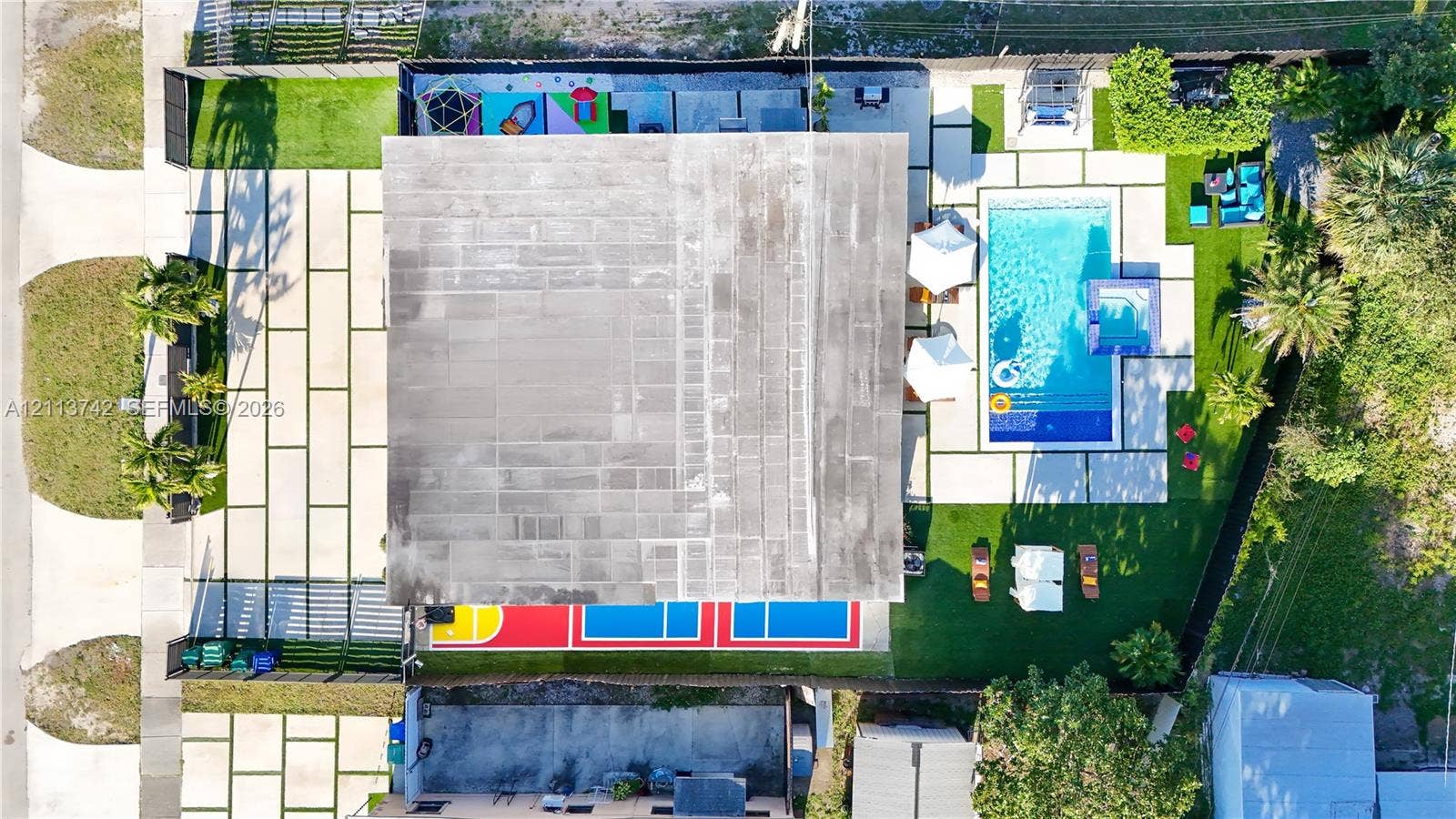 1930 NW 163rd St Road, Miami Gardens, FL 33054 Aerial view of property featuring a swimming pool, integrated spa, multi-sport court, and paved patio surfaces with turf accents