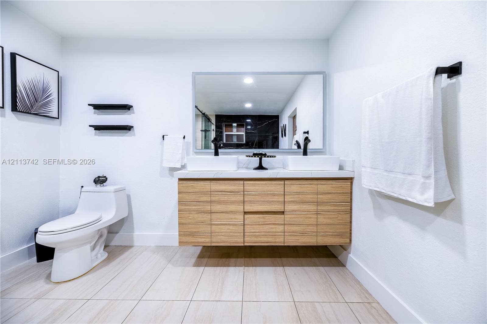 1930 NW 163rd St Road, Miami Gardens, FL 33054 Floating wood-finish vanity with dual vessel sinks, stone-surface countertop, and matte black hardware