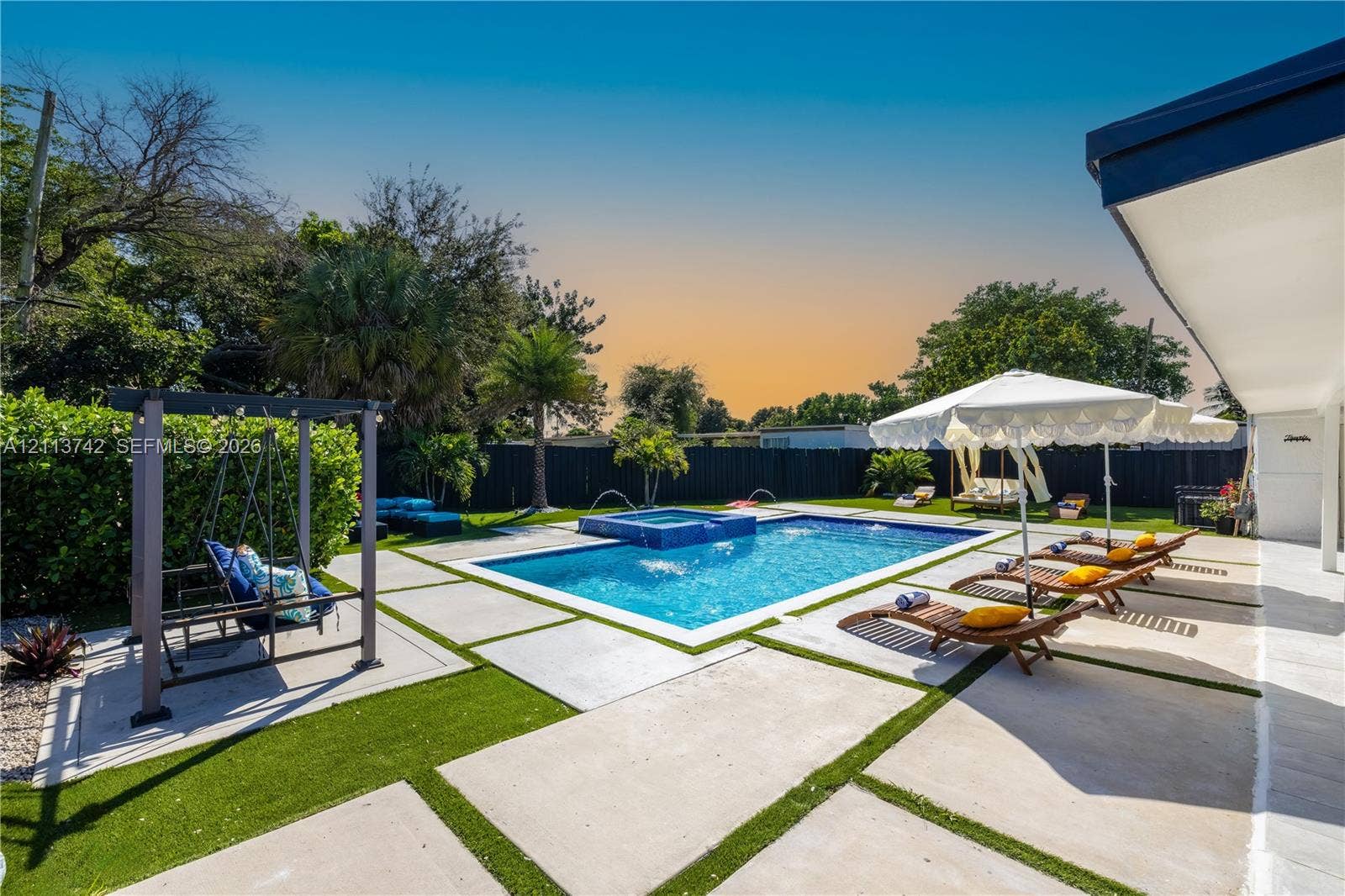 1930 NW 163rd St Road, Miami Gardens, FL 33054 Rear yard featuring a rectangular swimming pool with an integrated spa, concrete paver decking, and perimeter privacy fencing