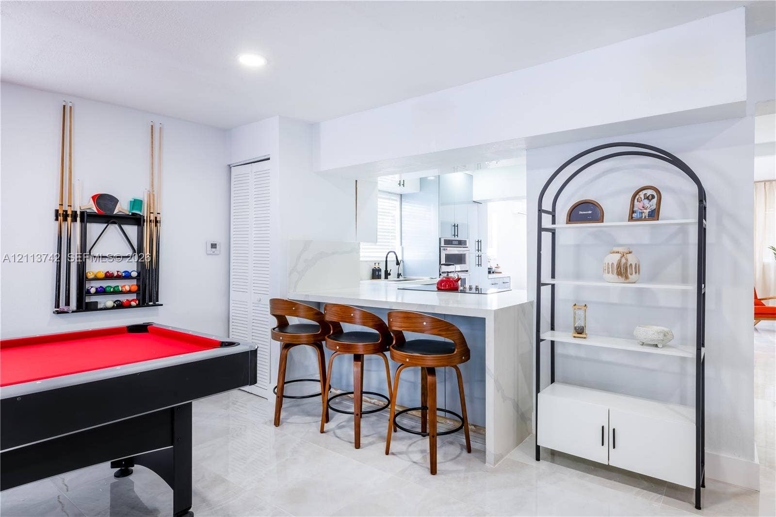 1930 NW 163rd St Road, Miami Gardens, FL 33054 Kitchen peninsula featuring a stone-look waterfall countertop, light-reflective stone-finish flooring, and recessed ceiling lighting