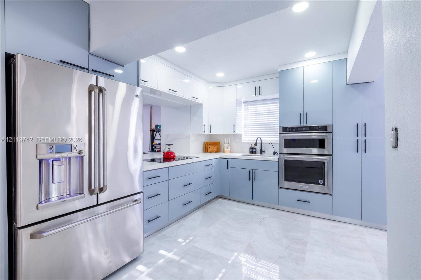 1930 NW 163rd St Road, Miami Gardens, FL 33054 Kitchen featuring light blue and white slab-style cabinetry, stainless steel double wall oven, stainless steel refrigerator, stone-surface countertops, and light-toned tile flooring
