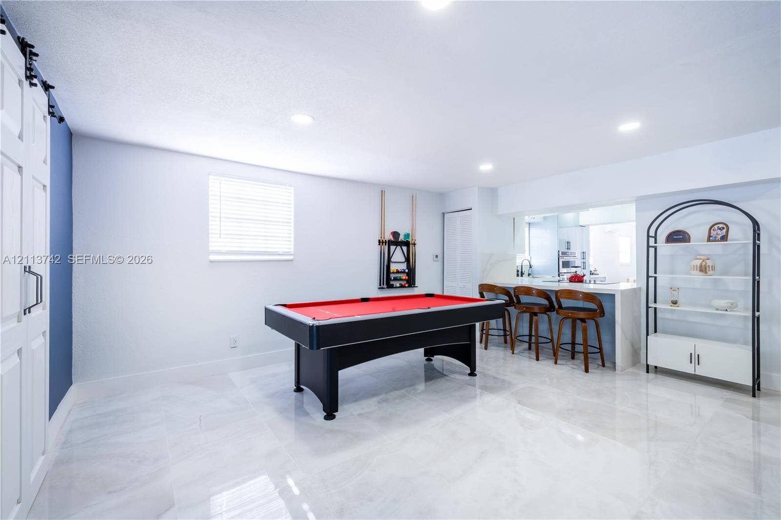 1930 NW 163rd St Road, Miami Gardens, FL 33054 Polished large-format tile flooring, built-in breakfast bar with stone-finish countertop, sliding barn-style door, and recessed lighting