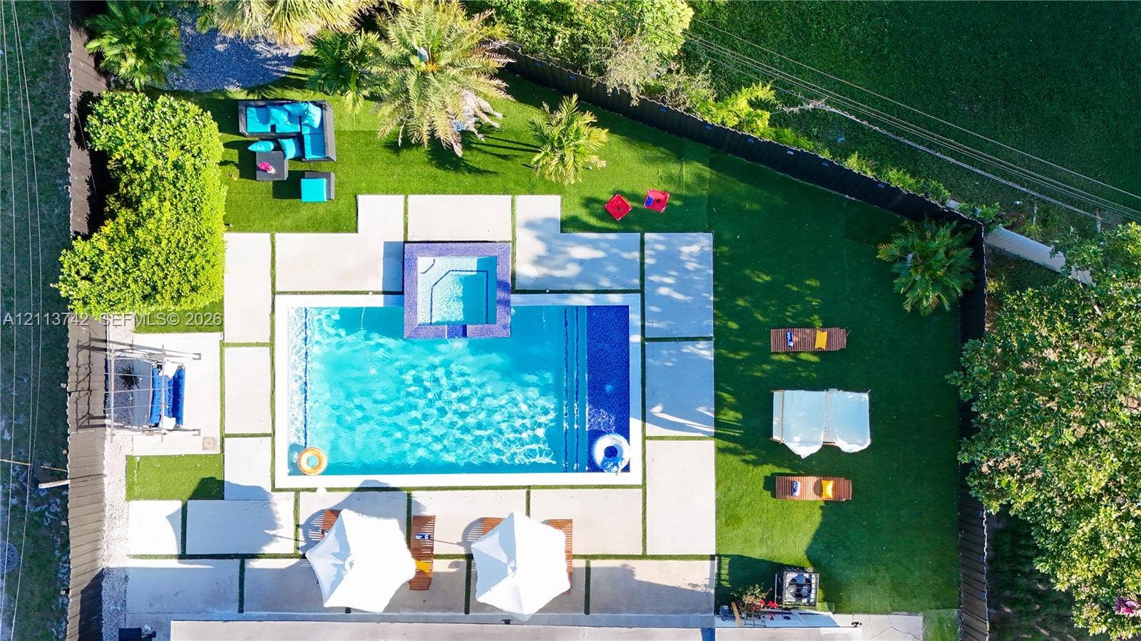 1930 NW 163rd St Road, Miami Gardens, FL 33054 Backyard featuring a swimming pool with integrated spa, concrete paver decking, and manicured turf