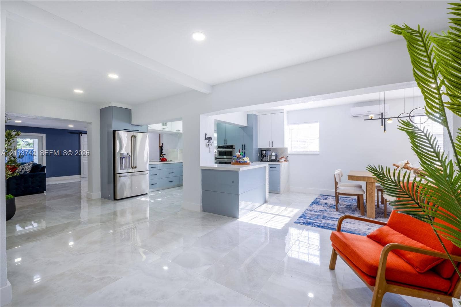 1930 NW 163rd St Road, Miami Gardens, FL 33054 Kitchen featuring a central island with a solid-surface countertop, high-gloss cabinetry, recessed lighting, and stainless steel appliances, complemented by large-format polished flooring